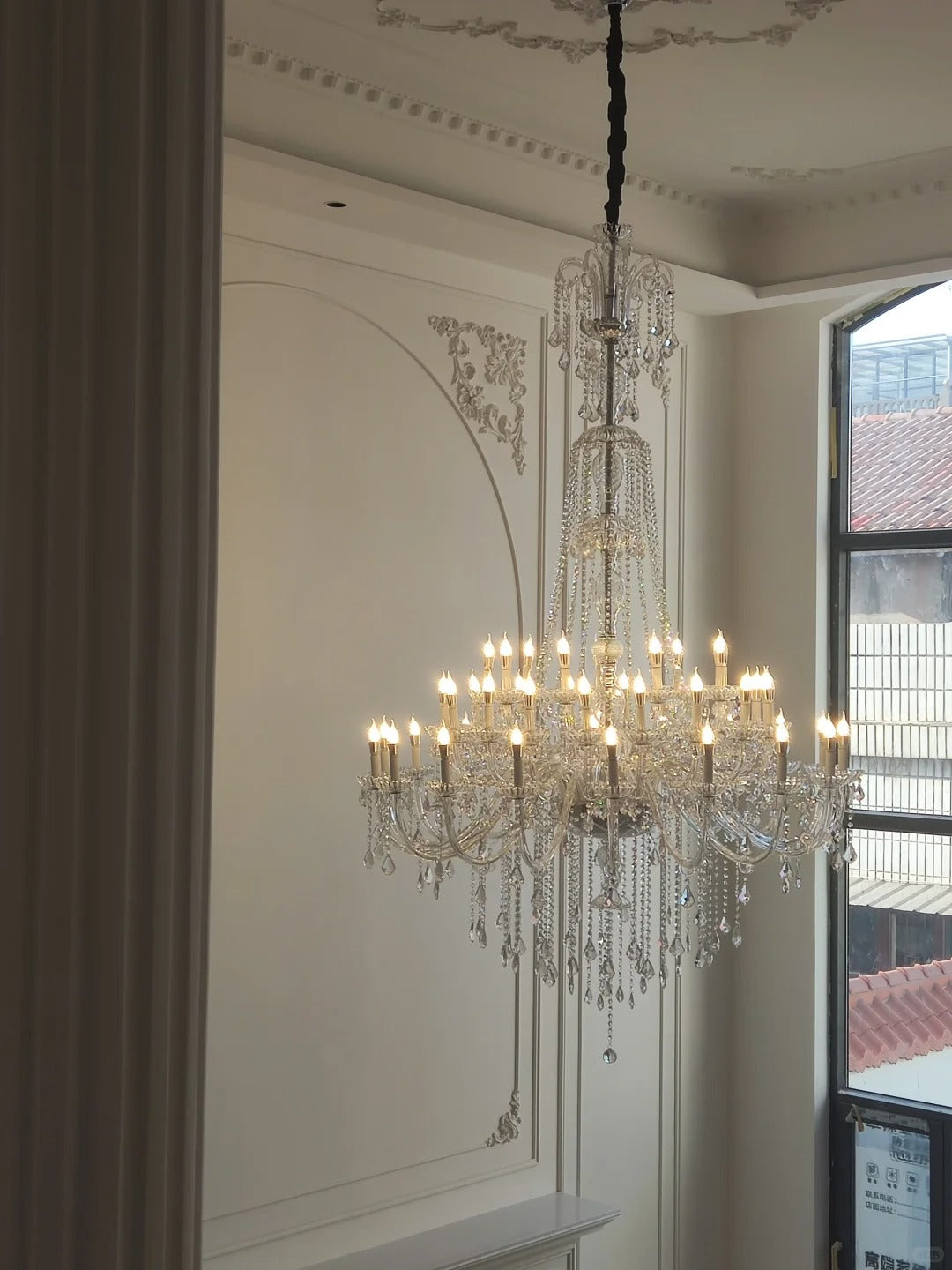 Large crystal candle-style chandelier installed in a double-height living room