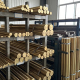 Raw brass rods and bars stacked on racks in a metalworking workshop. General installation or material reference; not a configuration photograph.